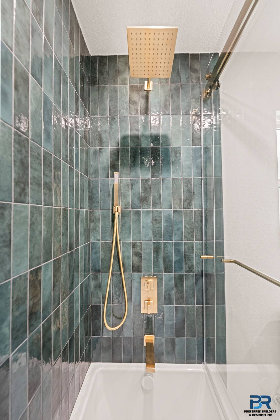 Green tile shower with brass fixtures in a remodeled San Jose bathroom