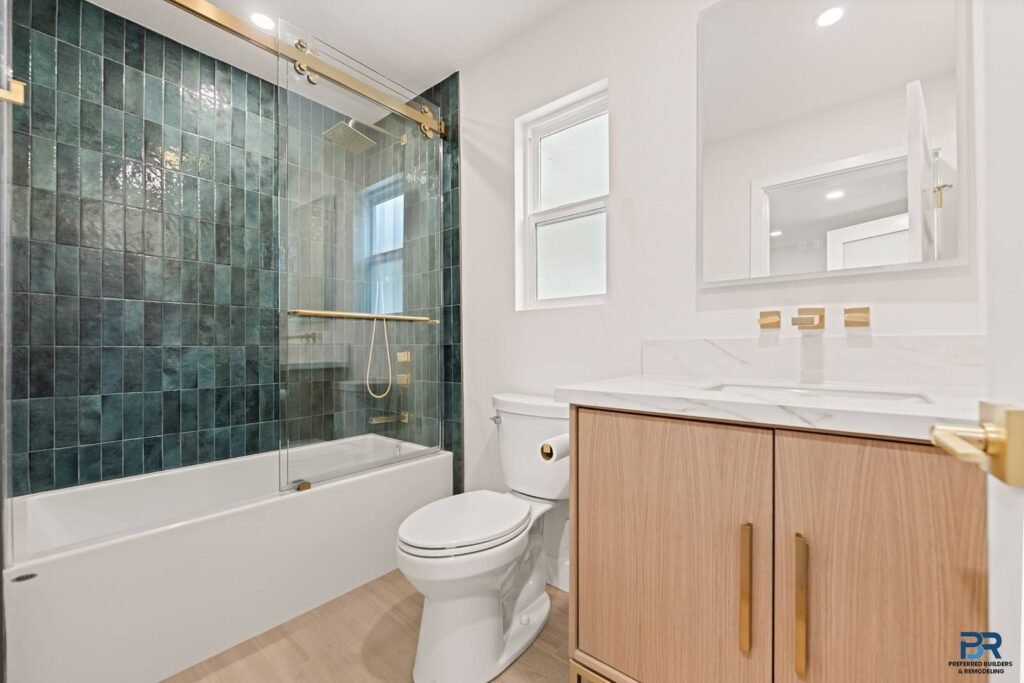 Remodeled bathroom with green tile, a tub and a wood vanity in San Jose