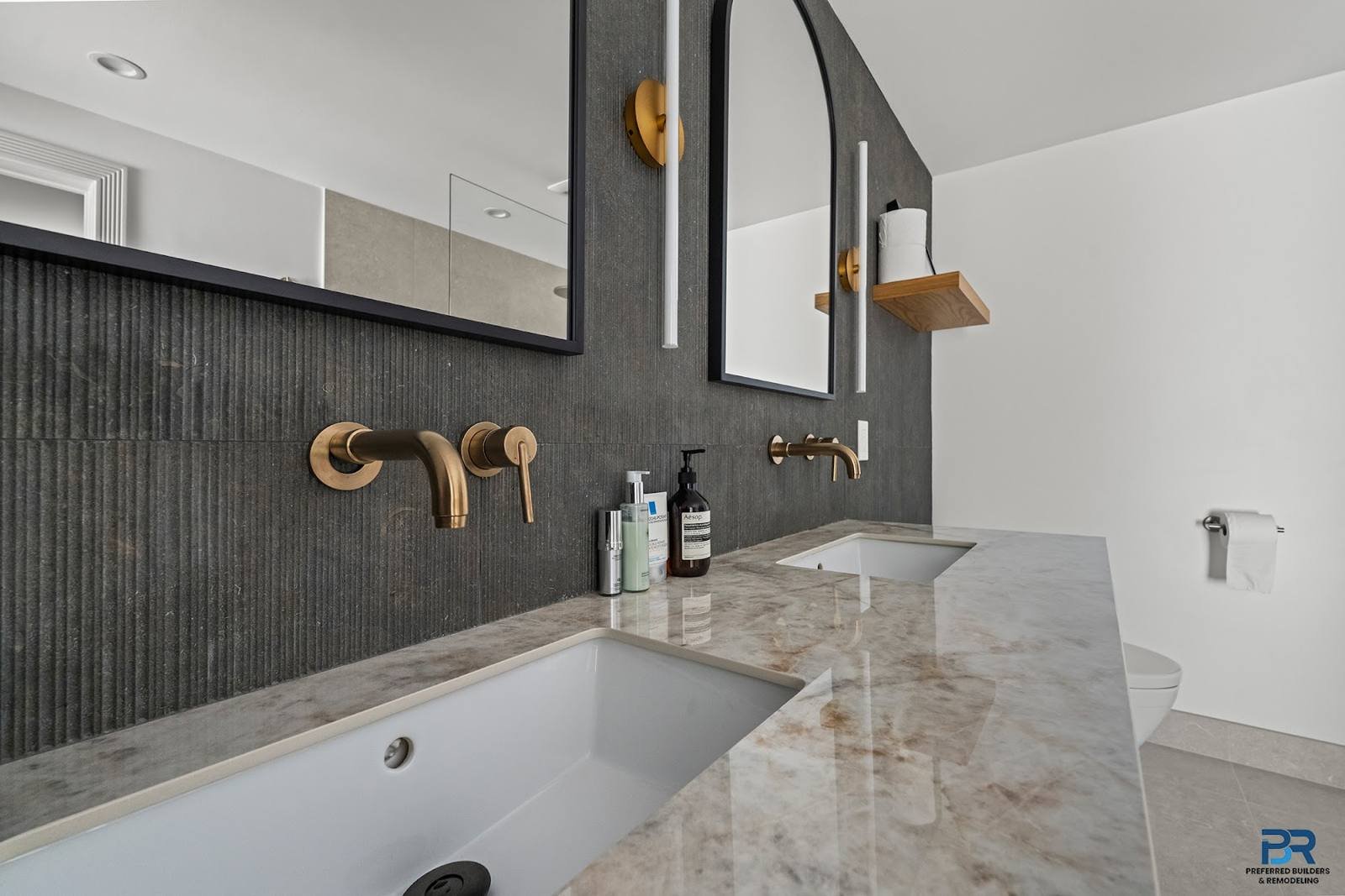 Vanity with an arched mirror, dark vertical tile and brushed brass faucet in a San Carlos whole-house remodel