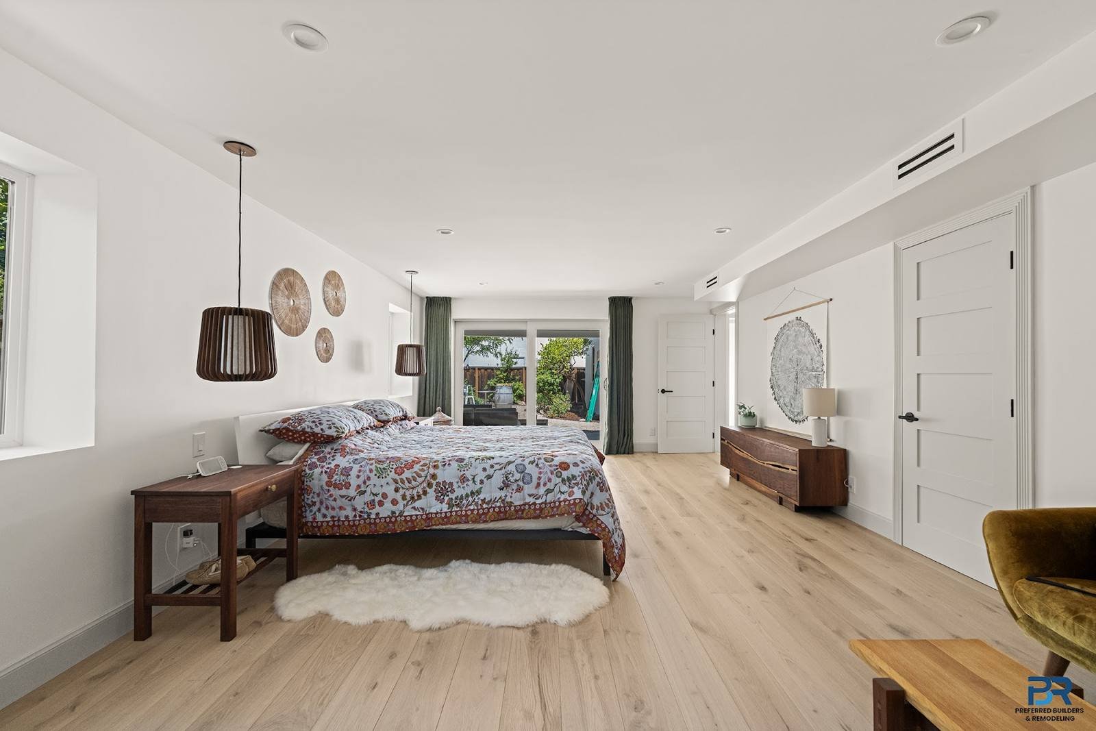 Lower-level bedroom with light wood flooring and a sliding glass door in a San Carlos whole-house remodel